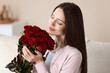 © New Africa - Woman with bouquet of red roses indoors