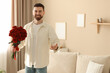 © New Africa - Handsome man with bouquet of roses at home. Space for text