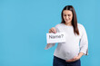 © New Africa - Pregnant woman holding card with word Name and question mark on light blue background, space for text