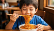 © CrazyJuke - Joyful Noodle Delight: A young child savoring a bowl of delicious noodles with chopsticks, expressing pure joy and contentment. A warm, intimate moment of culinary enjoyment