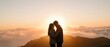 © Yuliia - Romantic couple silhouette embracing at mountain summit during golden hour sunrise with dramatic clouds and warm light for love and relationship concepts.
