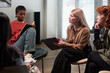 © pressmaster - Caucasian middle aged woman leading discussion with Black girl writing in notebook and Caucasian young adult women listening in group therapy or counseling session