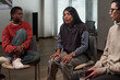 © pressmaster - Hispanic woman speaking during group therapy session with Black young woman and Caucasian middle aged woman listening, seated in modern room with window blinds