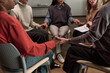 © pressmaster - Diverse group of women sitting in circle holding hands during support group session, showing unity and connection, multiethnic adults participating in discussion