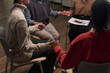 © pressmaster - Diverse group of middle aged and young adult women sitting in circle holding hands during support group session, participants engaging in mutual encouragement and emotional connection