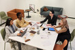 © pressmaster - Diverse group of young adult and middle aged women collaborating at table, discussing documents and digital tablet, engaging in business meeting in modern office