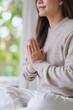 © Farknot Architect - Vertical closeup image of a woman put hands together in a prayer and meditating on the bed at home