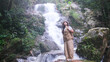 © Farknot Architect - Portrait image of a woman standing in front of the waterfall in the forest