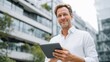 © Keo - A man holding a tablet in front of a modern building.