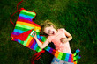 © Westend61 - Happy girl holding colorful kite while lying down in park