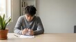 © Guillotine - Frustrated young asian man with messy black hair tearing up a university rejection letter in a minimalist room with a plant