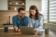 © Miljan Živković - Young couple managing household finances and online shopping together