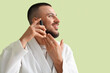 © Pixel-Shot - Handsome young man applying vitamin E serum on green background