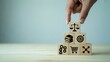 © HabibulAlamKhan - Hand placing wooden block with justice icon on a stack of business symbols representing law and ethics