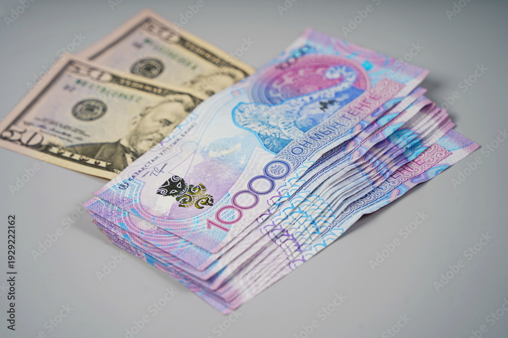 50 dollar bills and 10,000 tenge banknotes on a paper background ...