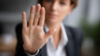 © Denis Yevtekhov - Stop hand sign woman in business suit with no gesture, sexual harassment and violence prevention in office workplace, defensive stance display, faceless professional, defocused background, with