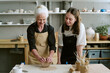 © AnnaStills - Senior Caucasian woman shaping clay while young adult woman observing in pottery studio, both standing at workbench with various sculpting tools and ceramics