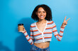 © deagreez - Young chic woman holding coffee and making peace sign against blue background