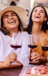 © Xavier Lorenzo - Young women friends enjoying wine and food outdoors. Female friends sharing tapas and drinks at an outdoor cafe in a European street. Lifestyle and travel concept.