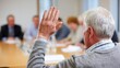 © Emilio - Senior man raising hand during town meeting. Community member participating in public discussion at municipal conference table