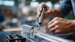 © Anastasiia Havelia - Close-up of a technician's hands using a precision screwdriver to fix a metallic joint of a booth frame, Professional Stand Assembly, blurred industrial crates in background, sharp