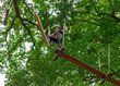 © Stefanie - Woman stepping onto rope obstacle in high ropes course in forest
