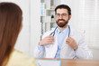 © New Africa - Woman having appointment with doctor at wooden desk in clinic, closeup