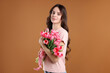 © New Africa - Portrait of young woman with bouquet of pink tulips on brown background