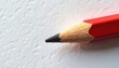 © miss irine - Red pencil tip sharpened on white textured paper. Classic drawing tool ready for writing or art. Simple object for schoolwork or office tasks. This is a single writing instrument.