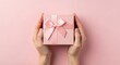 © Sania - Pink gift box with ribbon held by female hands.