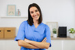 © Xavier Lorenzo - Portrait of a confident young nurse smiling with crossed arms, showcasing professionalism and healthcare expertise in a bright medical office setting