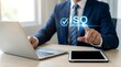 © Nest - A professional businessman in a blue suit works at a desk, pointing to a glowing virtual ISO CERTIFICATION display, emphasizing quality management.