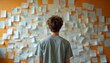 © Pete - Person faces wall covered in papers and notes. Represents overwhelm, decision paralysis, creative block, or organizing thoughts and ideas. Shows mental challenge and need for clarity.