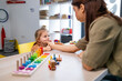 © littlewolf1989 - Speech therapist assisting a young girl with oral motor exercises, promoting improved speech development and communication skills during an education session in a learning environment