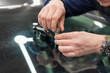 © Dmitry Presnyakov - Mechanic using repairing equipment to fix damaged windshield, windshield repairing. Close up Car glaze worker fixing and repairing a windshield or windshield of a car at a garage service station.