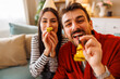 © Impact Photography - Couple having fun wearing party hats blowing party whistles while celebrating birthday at home