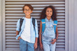 © InsideCreativeHouse - Front view of smiling school kids preteen boy and girl diverse children in smart casual clothes looking at the camera posing at the street outside standing over grey background