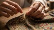 © Audax - A person's hands sewing and restoring a piece of vintage embroidered fabric.