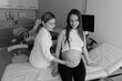© Anton - Black and white photograph of a female gynecologist consulting a young pregnant woman in a modern clinic. Professional prenatal examination with medical instruments highlighting trust, expertise