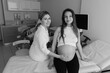 © Anton - Black and white photograph of a female gynecologist consulting a young pregnant woman in a modern clinic. Professional prenatal examination with medical instruments highlighting trust, expertise
