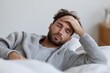 © Andrii Zastrozhnov - Young caucasian male relaxing in bed with hand on forehead