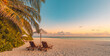 © icemanphotos - Beautiful tropical sunset scenery with two sun beds loungers umbrella under palm tree white sand sea view horizon colorful twilight sky for inspirational beach resort hotel tourism travel art design