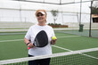 © Angelov - mature woman playing padel on outdoor court.