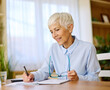 © Lumos sp - Portratit of a senior mature businesswoman writing during meeting in office