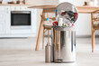 © Pixel-Shot - Full trash bin on floor in modern kitchen