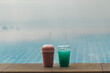 © StockMediaSeller - Two colorful cold drinks on pool edge with blurred infinity pool and soft sky background creating minimal tropical refreshment scene with wide copy space and calm travel mood