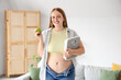© Pixel-Shot - Young happy overweight woman in tight jeans with fresh apple and scales at home