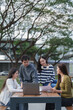 © crizzystudio - University students collaborating on laptop outdoors studying project