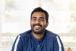 © fizkes - Head shot portrait young Indian bearded man dressed in casual blue shirt laughing, looking into distance, enjoy carefree day-off, light-hearted moments alone at home, exudes happiness and friendliness