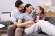 © New Africa - Pregnant woman, her husband and daughter on sofa at home